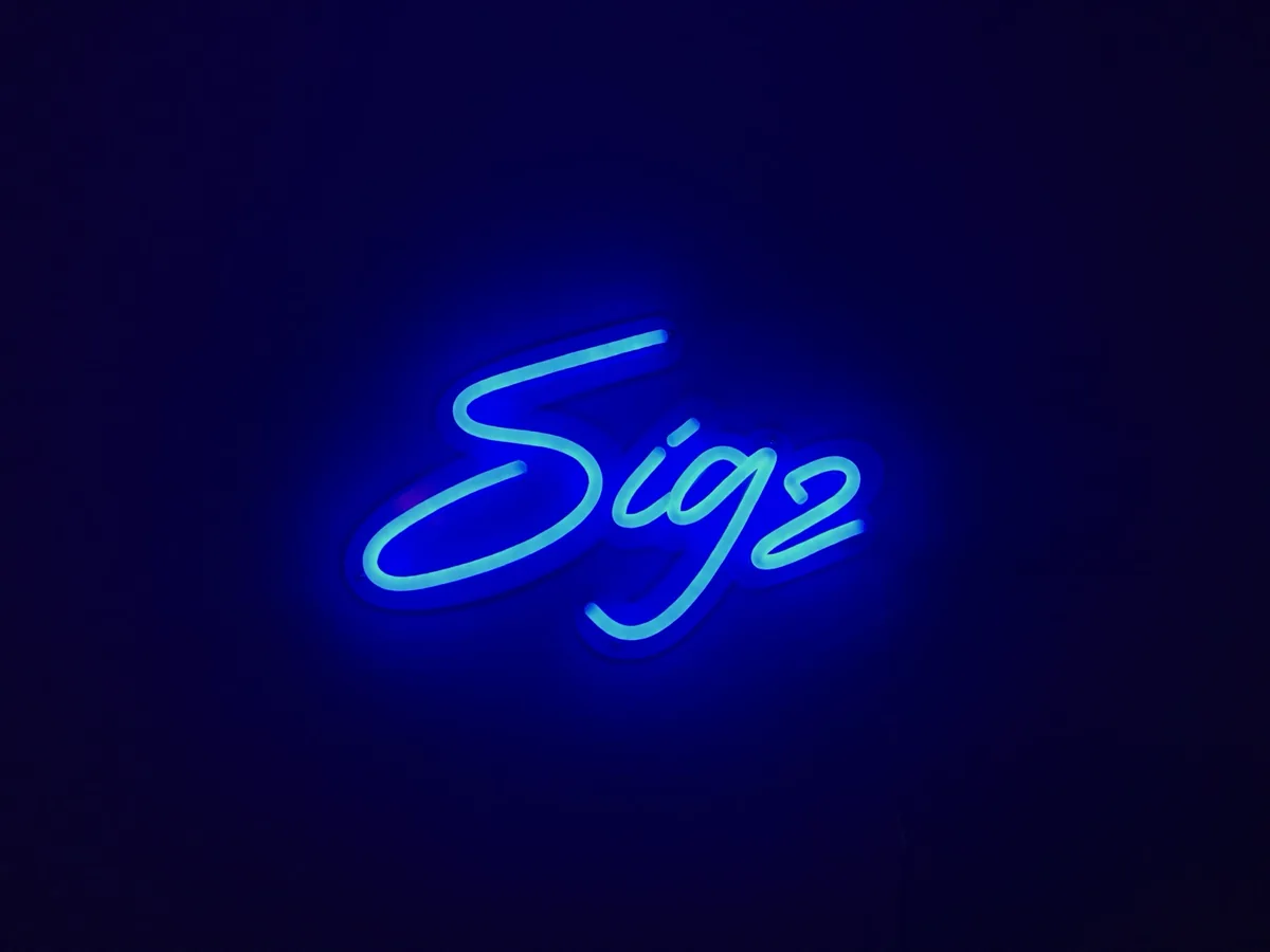 A blue neon sign reading Sigz, glowing in a dark room.